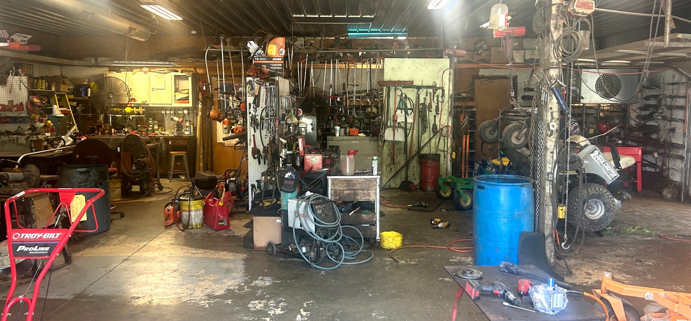 Repair bay at M&M Mower Repair with a mower on the lift and tools visible