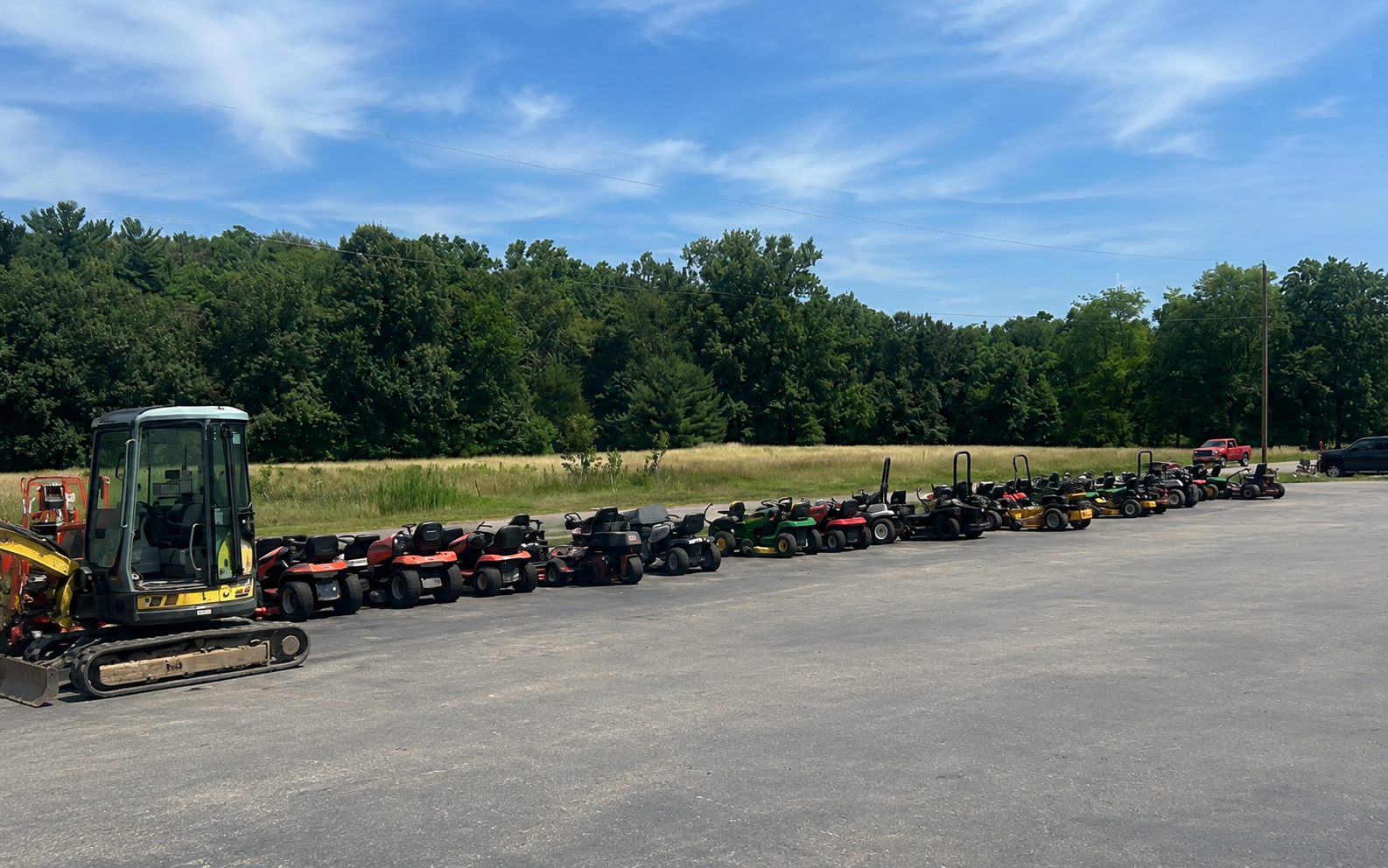 Long row of used mowers and equipment lined up on the lot at M&M Mower Repair